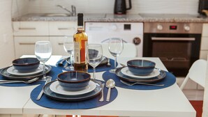 Mesa de comedor dispuesta con platos, cuencos y cubiertos azules, una botella de vino y copas.