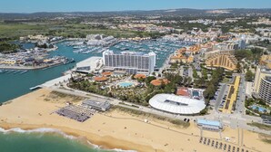 Vista aérea de una ciudad costera con un puerto deportivo, hoteles y una playa.