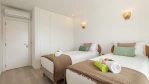 Une chambre d’hôtel avec deux lits, une armoire, un luminaire fixé au mur et une porte.