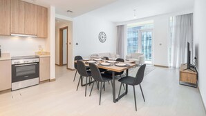 Een moderne keuken met een Bosch fornuis, een eethoek met een houten tafel en zwarte stoelen, en een groot raam met gordijnen.