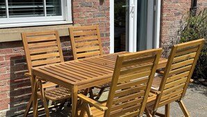 A wooden outdoor table and chairs set against a brick wall with a window and door. - Dog & Family Friendly Ground Floor Apartment, 10 mins walk to beach (Primrose Valley)