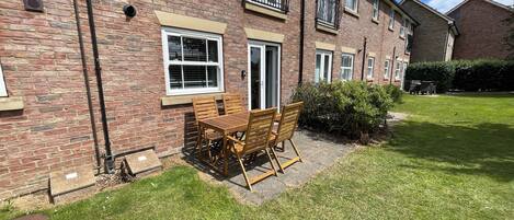 A brick building with a patio table and chairs, a window, and a door.