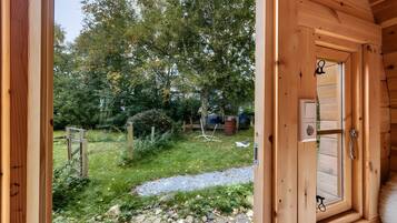 A wooden door leading to a garden with a gravel path, trees, and a wooden fence.