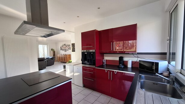 A modern kitchen with red cabinets, stainless steel appliances, and a black countertop. - Maison de Guise, pets welcome (Guise)
