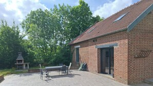 A brick building with a tiled patio, outdoor seating, and a chimney. - Maison de Guise, pets welcome (Guise)