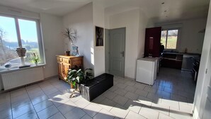 A spacious living area with a large window, a wooden cabinet, and a potted plant. - Maison de Guise, pets welcome (Guise)
