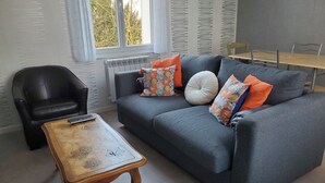 A living room with a grey sofa, black armchair, and a wooden coffee table. - La petite Chamarande, peaceful cottage with river view, close to Tours & Amboise (Montlouis-sur-Loire)