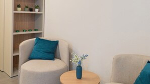 A modern living room with a round coffee table, two armchairs, a bookshelf, and a small side table with a vase. - Imperium Suite Trevi (Rome)