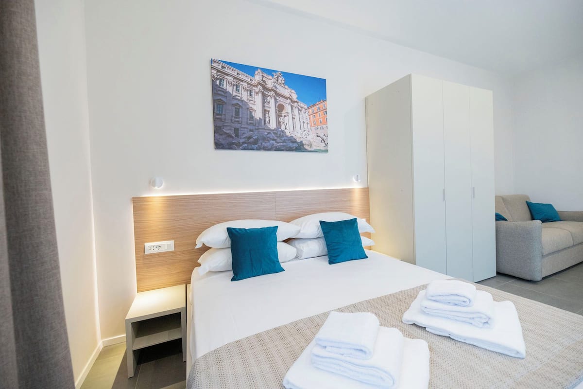 Une chambre d’hôtel avec un lit, un canapé, une armoire et un tableau au mur.