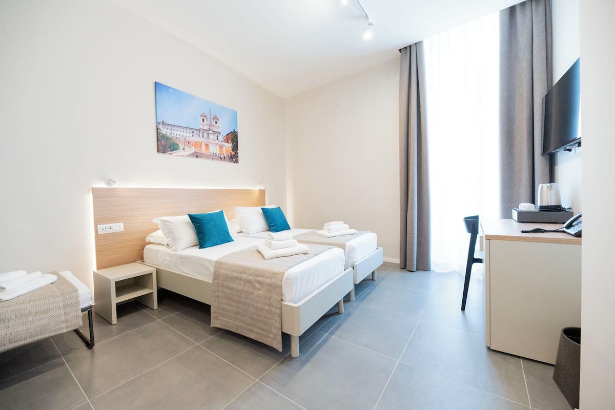 Une chambre d’hôtel avec un lit, un bureau, une chaise, une télévision et un tableau au mur.