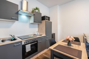 A modern kitchen with a sink, stove, oven, microwave, and cabinets.