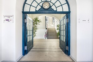 Ein Hotel Eingang mit einer Uhr, einer Treppe und Wegweisern.