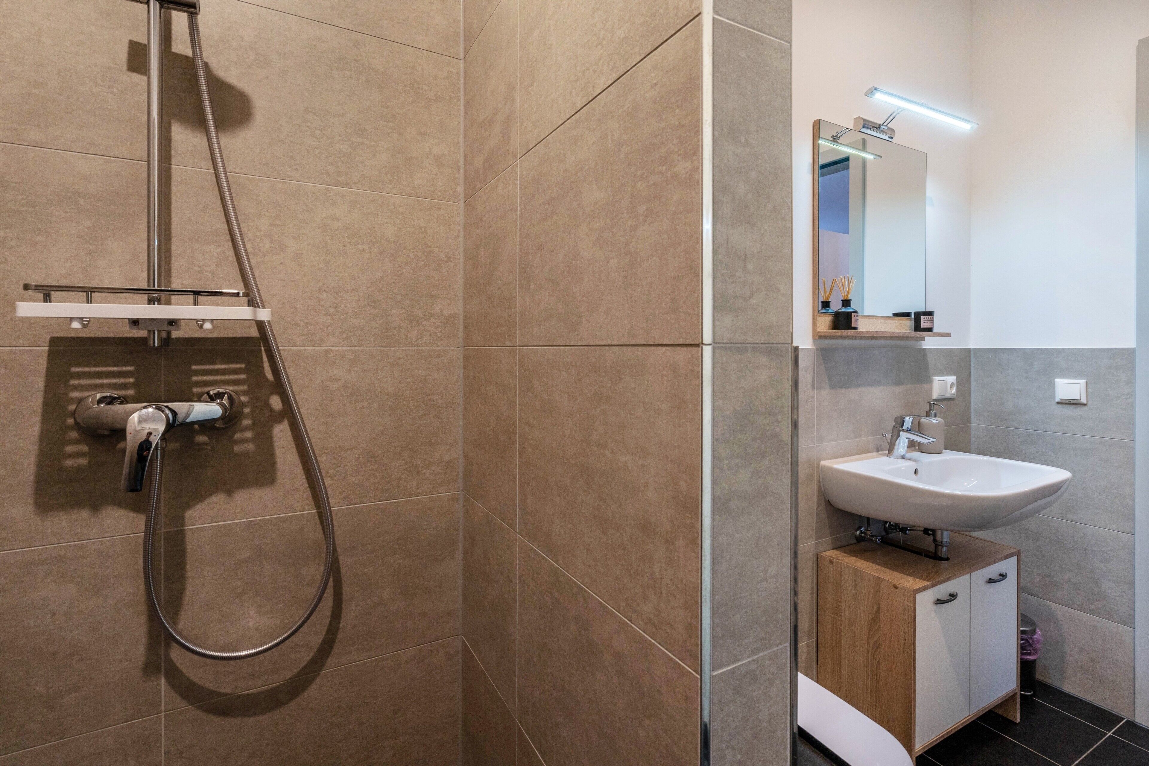 Un bagno con doccia, lavandino e specchio.