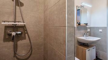 Un bagno con doccia, lavandino e specchio.