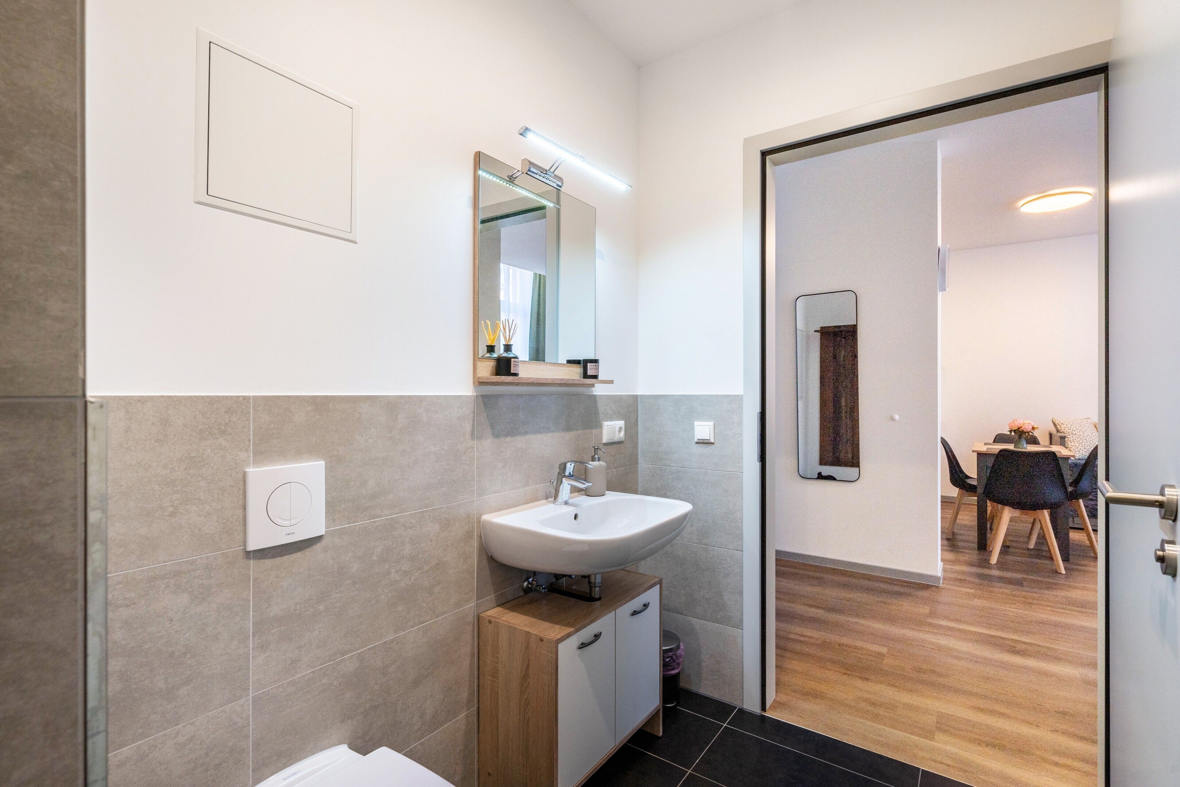 Un baño moderno con lavamanos, espejo e inodoro.