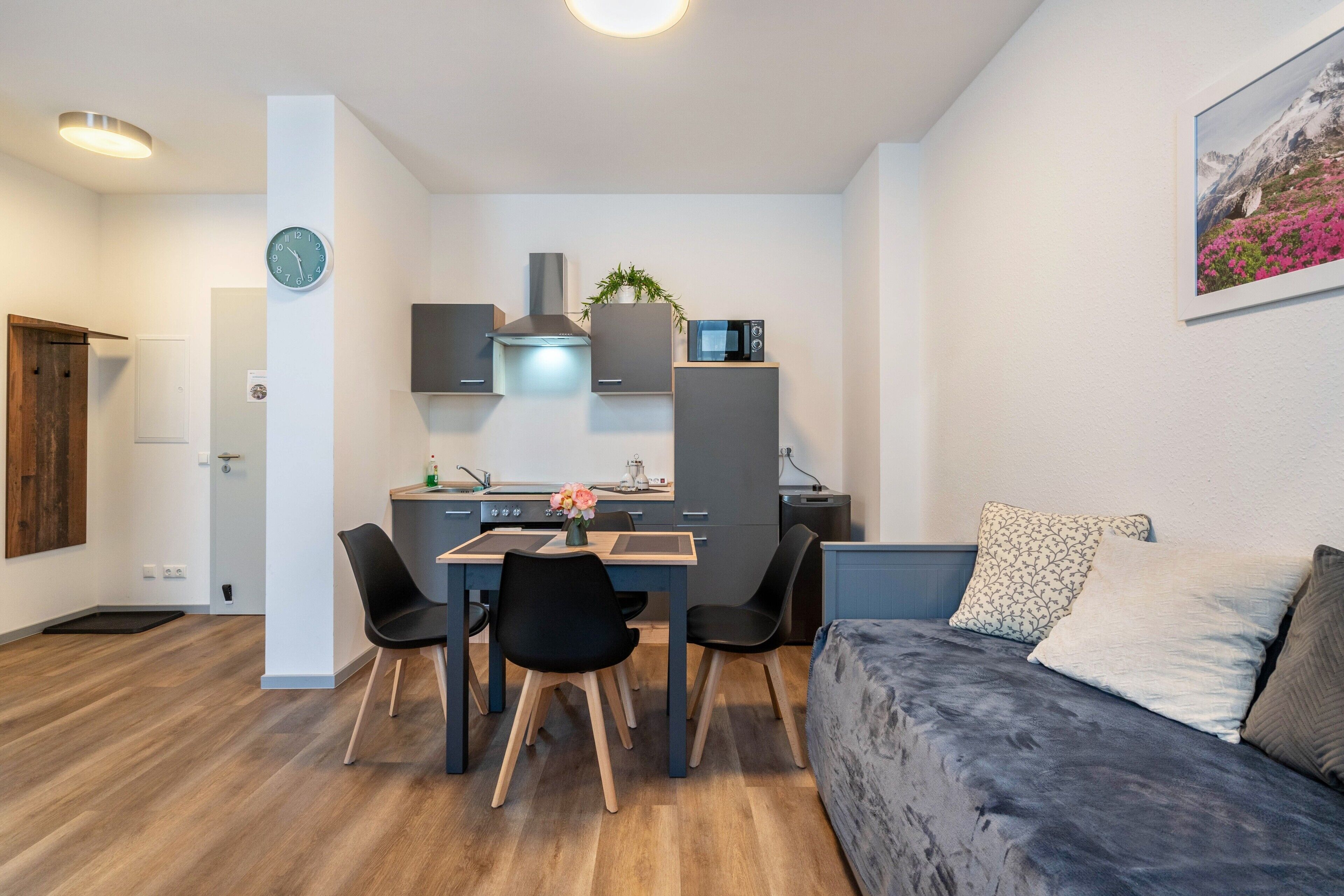 Eine moderne Küche mit Essbereich, einer Couch und einer Uhr an der Wand.