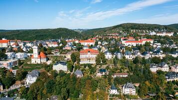 A town with a mix of residential and historical buildings, surrounded by hills and greenery.