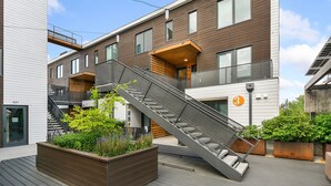 A modern building with a staircase leading to an upper level, surrounded by greenery and a clear sky. - The Overlook | Luxe Old Town Condo w/ King Suite (Fort Collins)