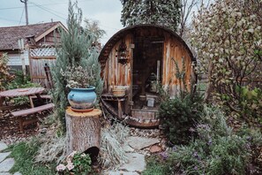A rustic wooden structure with a circular roof, surrounded by a garden with various plants and a wooden table. - Boho Art cottage in hip Bay View, Milw neighborhood- 3bed, Sauna, Hot Tub (Milwaukee)