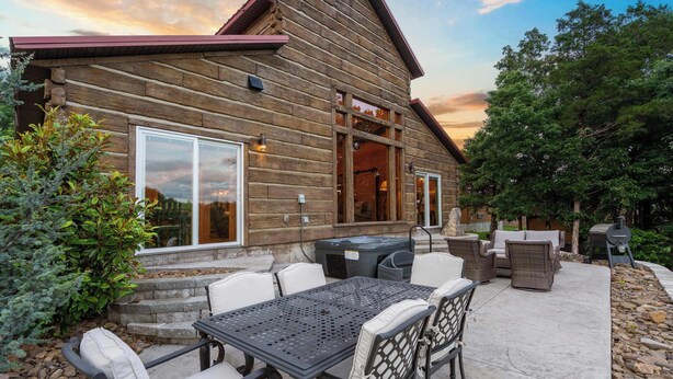 A log cabin with a patio area featuring outdoor furniture and a hot tub. - Buffalo Lodge – Stay for 6 (Branson)