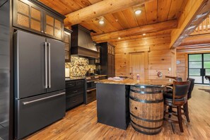 Une cuisine moderne dotée d’un grand réfrigérateur, de meubles en bois et d’un coin bar avec des tabourets.