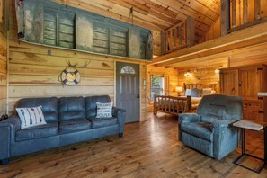 A wooden interior with a leather sofa, a recliner, and a dining area. - Antler Summit Trio – For 14 (Branson)