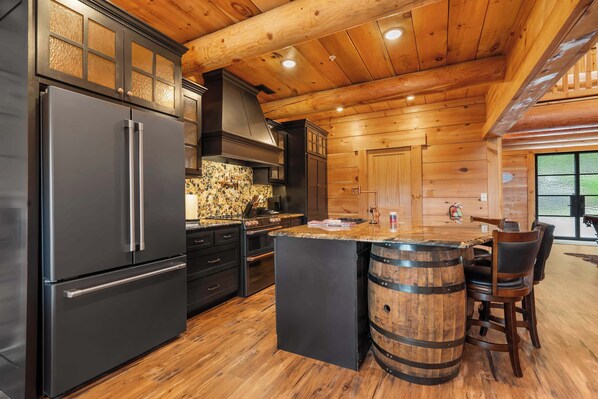 A modern kitchen with a large refrigerator, wooden cabinets, and a bar area with stools. - Antler Summit Trio – For 14 (Branson)