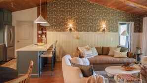 Una sala de estar acogedora con techo de madera, un sofá, una mesa de centro y un comedor con sillas y una mesa.