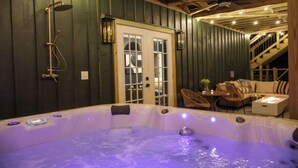Un jacuzzi en una cabaña de madera con una escalera, un comedor y vistas al exterior.