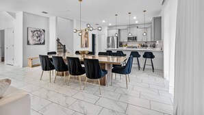 A modern kitchen with white cabinets, stainless steel appliances, and pendant lighting.