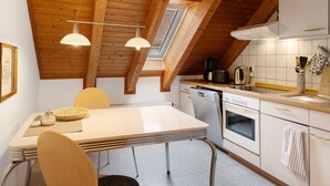 A kitchen with a wooden ceiling, a skylight, white cabinets, and a dining area with a table and chairs.