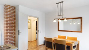 A dining area with a wooden table and chairs, a brick wall, and a mirror on the wall.