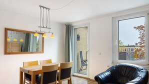 A modern room with a dining table, chairs, a black leather chair, a mirror, and a window with a view.