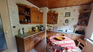 Une cuisine avec des meubles en bois, un dosseret carrelé et un coin repas avec une table mise pour deux personnes.