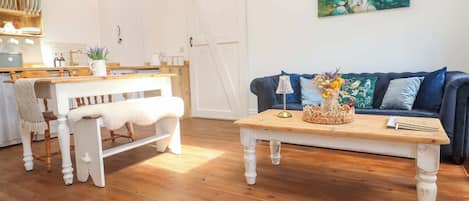 A cozy living room with a wooden bench, a coffee table with a vase of flowers, and a blue sofa.