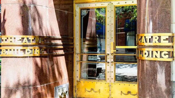 A theater entrance with a yellow door and columns.