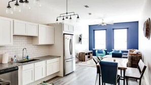 A modern kitchen with white cabinets, a built-in oven, and a dining area with a round table and chairs.