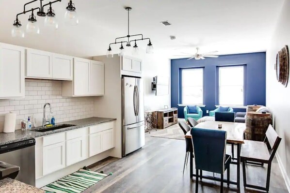 A modern kitchen with white cabinets, a built-in oven, and a dining area with a round table and chairs.