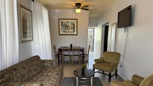 A living room with a sofa, two armchairs, a dining table with chairs, a ceiling fan, and a TV mounted on the wall. - 30 Day Minimum-3BR in Santurce-Near Beach UNIT 1 (San Juan)
