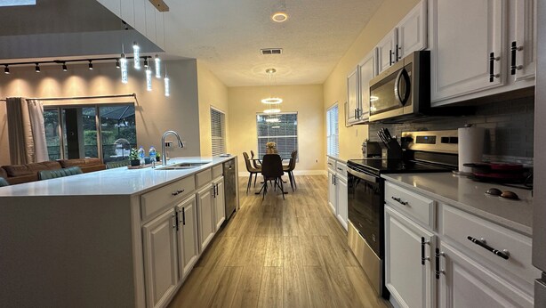 Une cuisine moderne avec des meubles blancs, un îlot central et des luminaires suspendus.