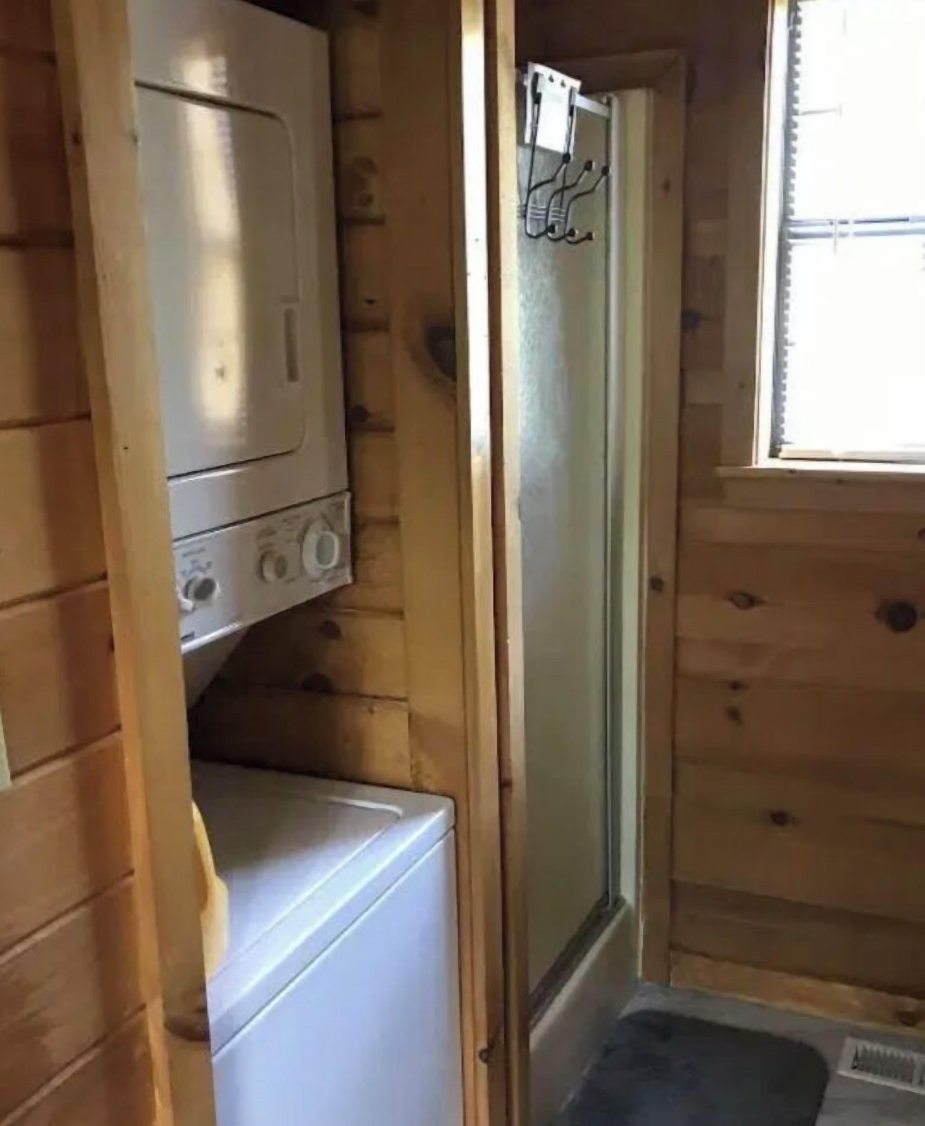 Pieni huone, jossa on pesukone, kuivausrumpu ja suihkukaappi.