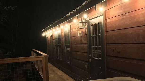Una cabaña de madera con jacuzzi y terraza.