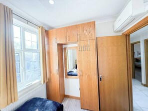 Een kamer met een bed, een kast, een spiegel en een raam.