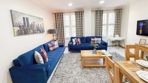 Ein Wohnzimmer mit zwei Sofas, einem Couchtisch und einem Esstisch mit Stühlen.