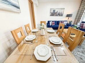 Een eethoek met een houten tafel gedekt voor zes personen, omringd door houten stoelen.