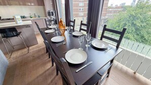 Un comedor con una larga mesa dispuesta para seis personas, con platos, cubiertos y vasos.