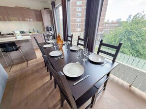 A dining area with a long table set for six, equipped with plates, cutlery, and glasses.