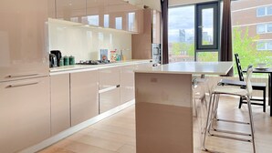 Una cocina moderna con una isla grande, electrodomésticos de acero inoxidable y vistas de la ciudad a través de un ventanal amplio.