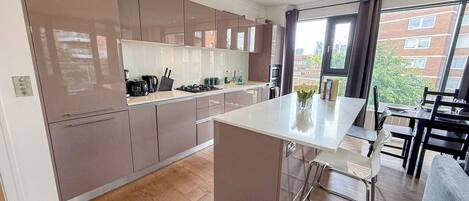 Een moderne keuken met een centraal eiland, inbouwapparatuur en een eethoek met uitzicht.