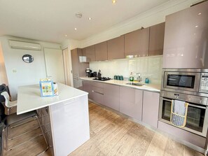 A modern kitchen with stainless steel appliances, a white countertop, and wooden flooring. - 3bdr + Balcony | London bridge, borough, the shard (London)